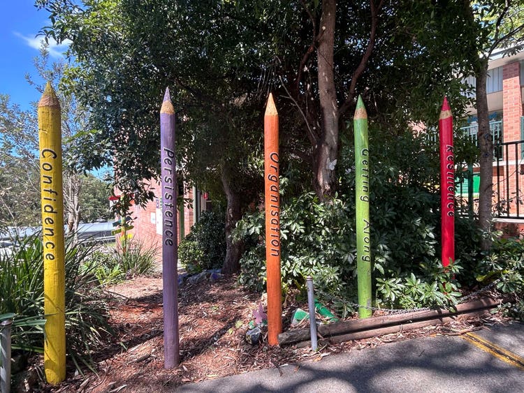 Yellow confidence pencil, purple persistence, orange organisation pencil, green getting along pencil, red resilience pencil statues in garden